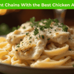 “Creamy Chicken Alfredo pasta served at top restaurant chains, showcasing the Best Chicken Alfredo in 2025 with fresh garnish and elegant plating.”